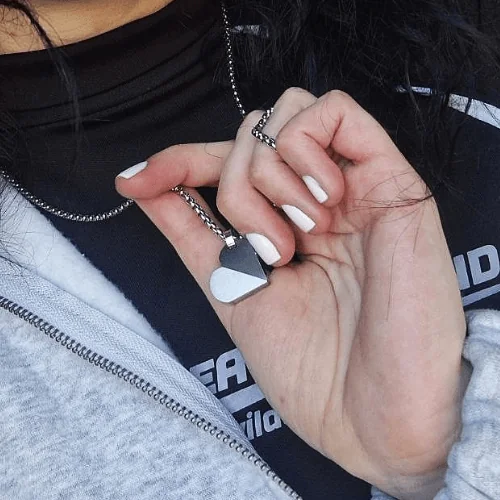 Жіноча рука тримає розкладену підвіску-трансформер HEART-TAG у формі серця на ланцюжку.