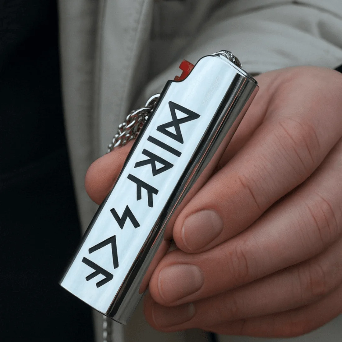 Сріблястий металевий чохол-кулон для запальнички BIC J3 з гравіюванням рун у руці.