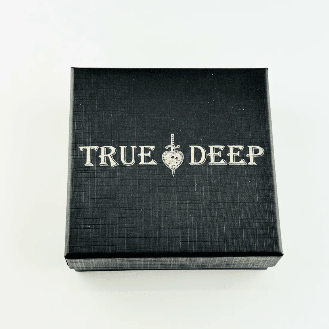 Подарункова коробка чорного кольору з гравіюванням бренду TRUE & DEEP та символом меча з серцем.