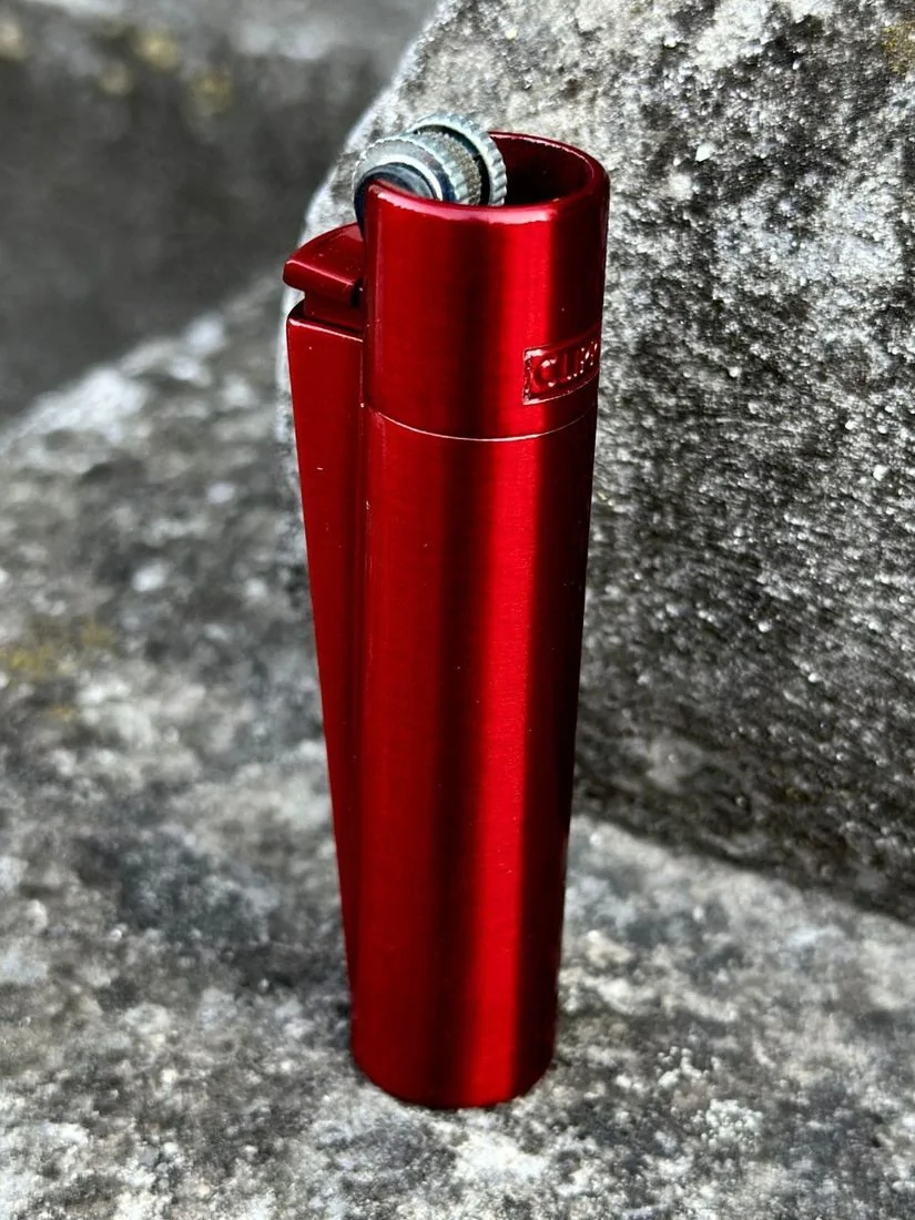 Червона металева запальничка Clipper Metall Red Devil на камені, на природі